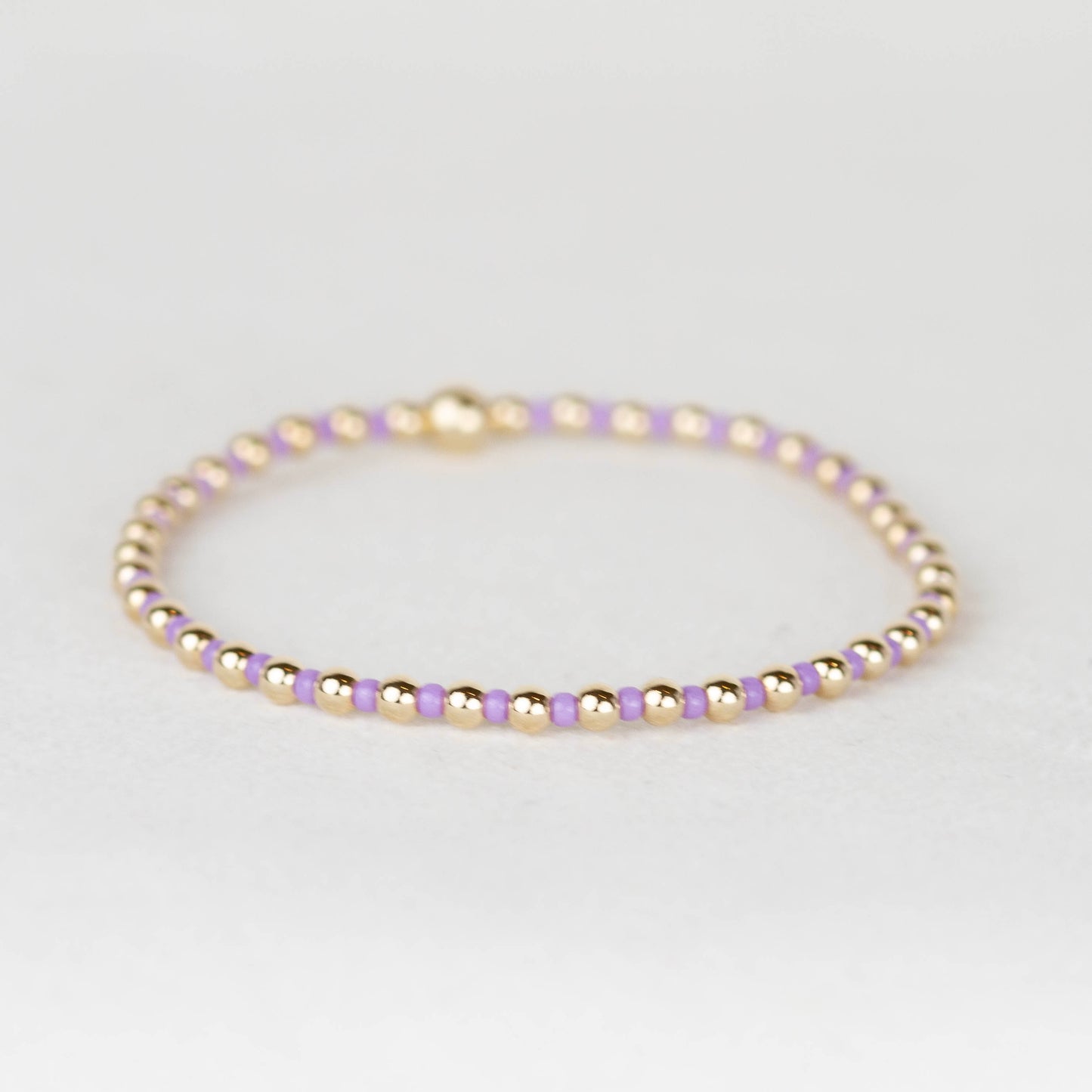 Amethyst purple Bella seed bead alternating with 14k gold filled or sterling silver beaded stretch bracelet 
