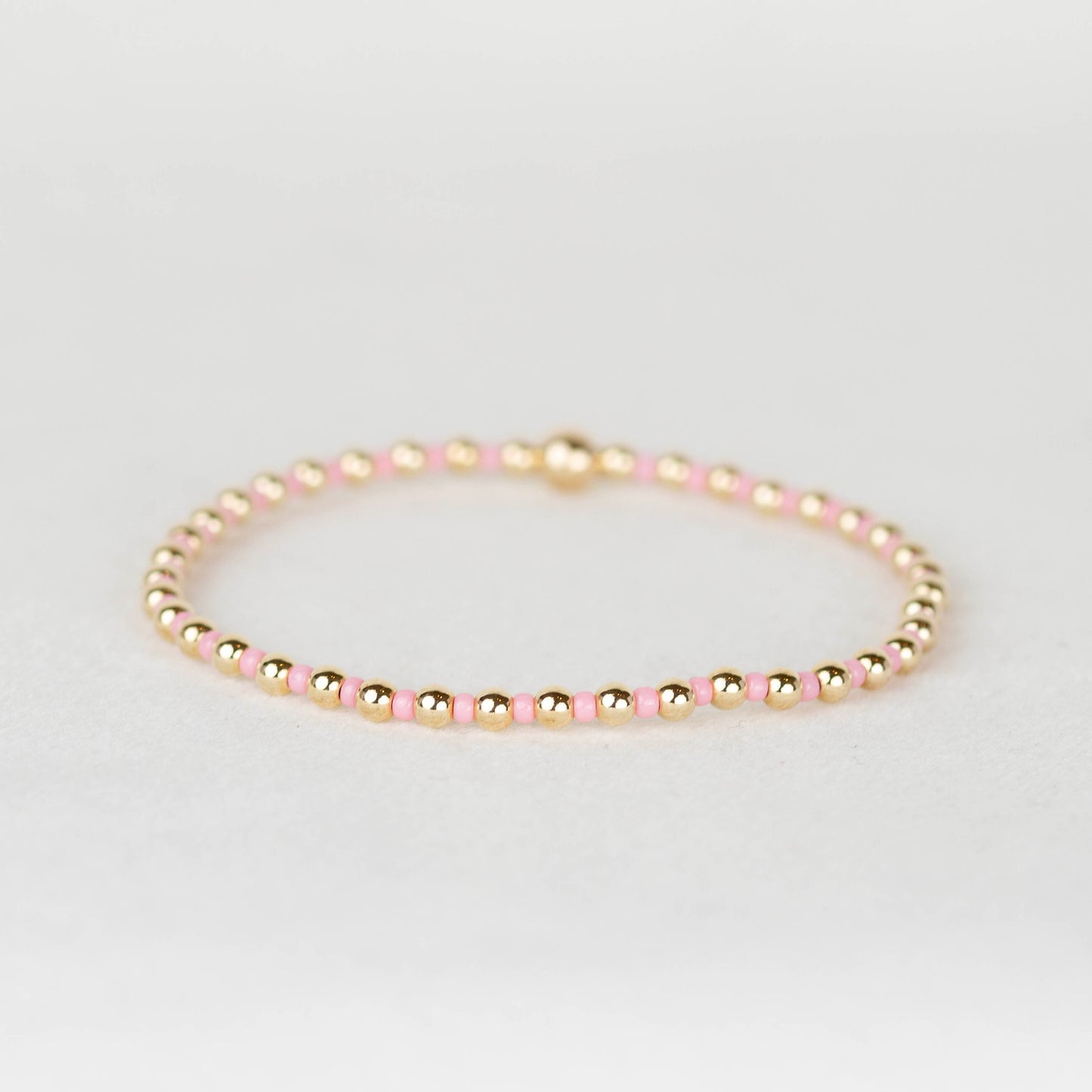 Pink Bella seed bead alternating with 14k gold filled or sterling silver beaded stretch bracelet 
