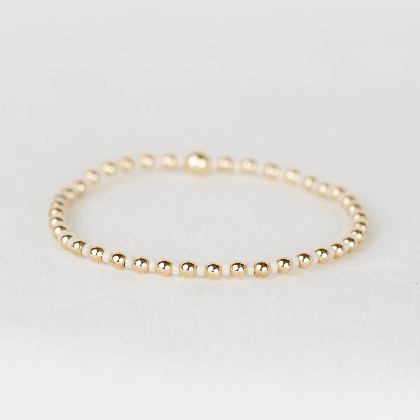 Cream Bella seed bead alternating with 14k gold filled or sterling silver beaded stretch bracelet