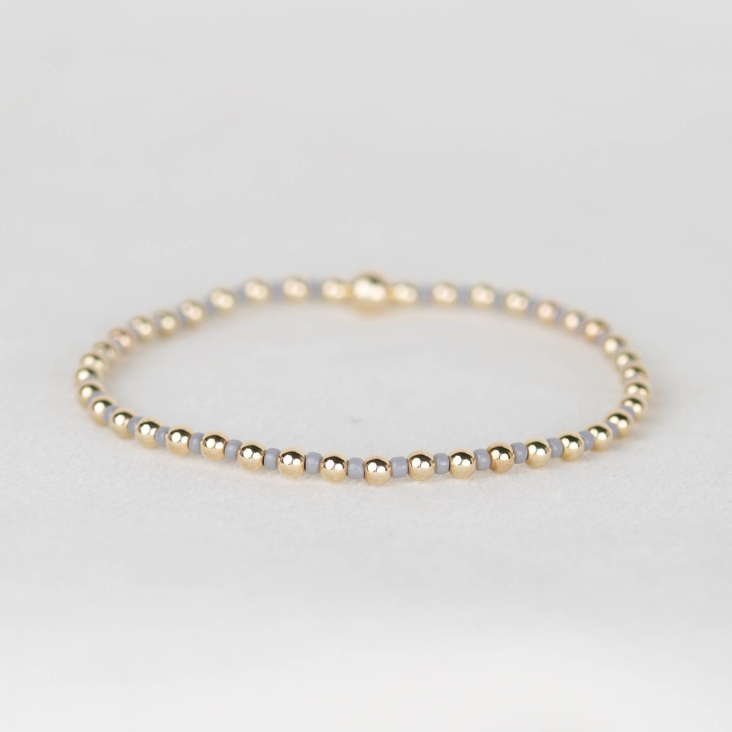 Light gray Bella seed bead alternating with 14k gold filled or sterling silver beaded stretch bracelet 
