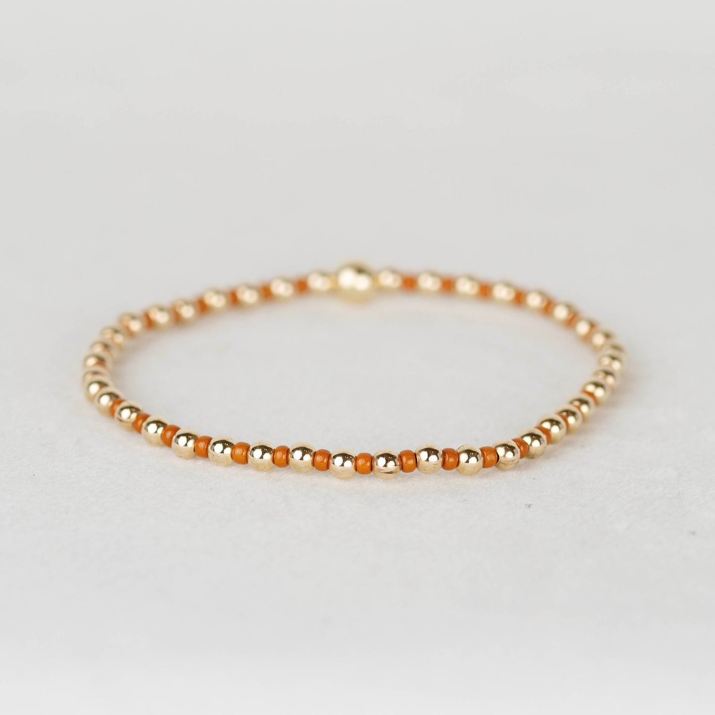 Orange Bella seed bead alternating with 14k gold filled or sterling silver beaded stretch bracelet 