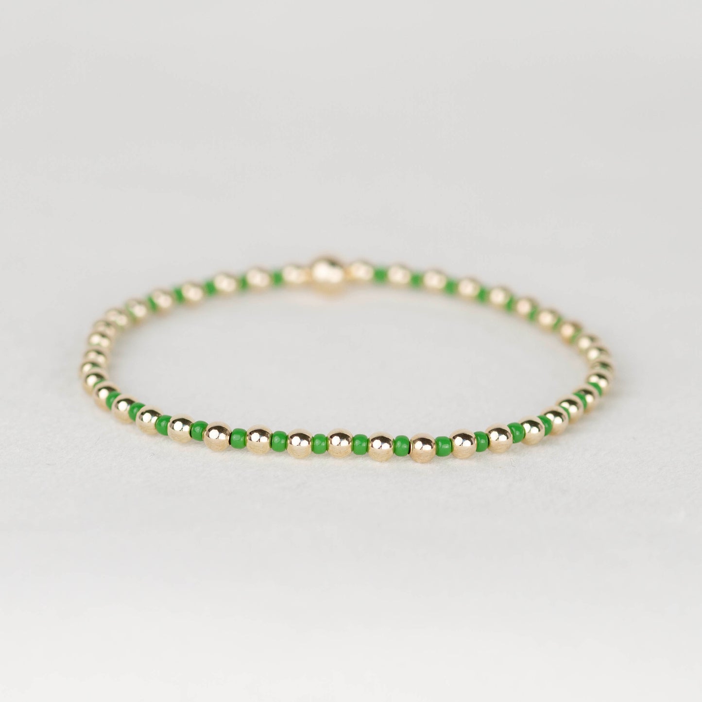 Green Bella seed bead alternating with 14k gold filled or sterling silver beaded stretch bracelet 
