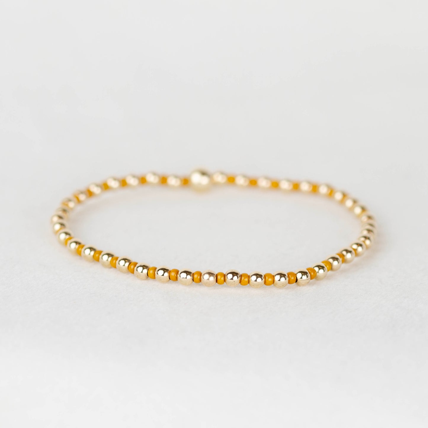 Mustard yellow Bella seed bead alternating with 14k gold filled or sterling silver beaded stretch bracelet 
