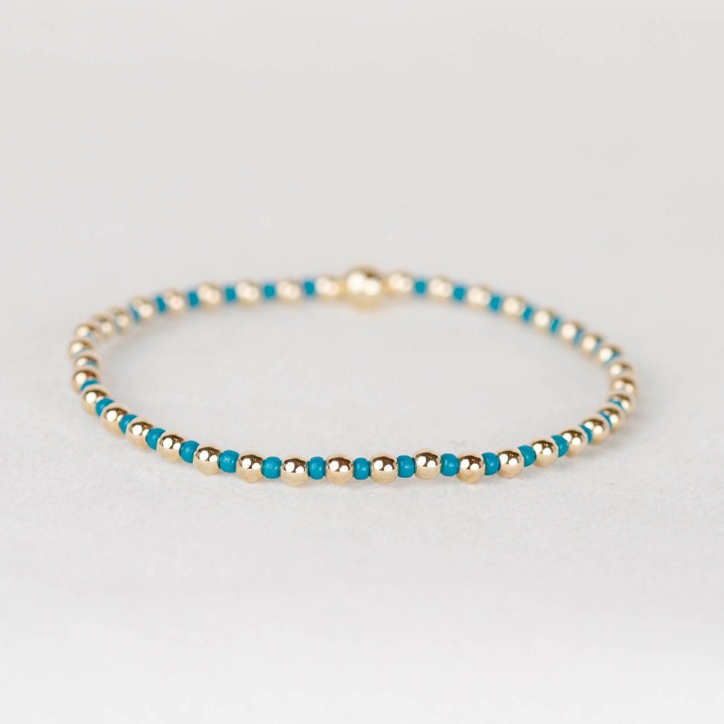 Teal bue Bella seed bead alternating with 14k gold filled or sterling silver beaded stretch bracelet 

