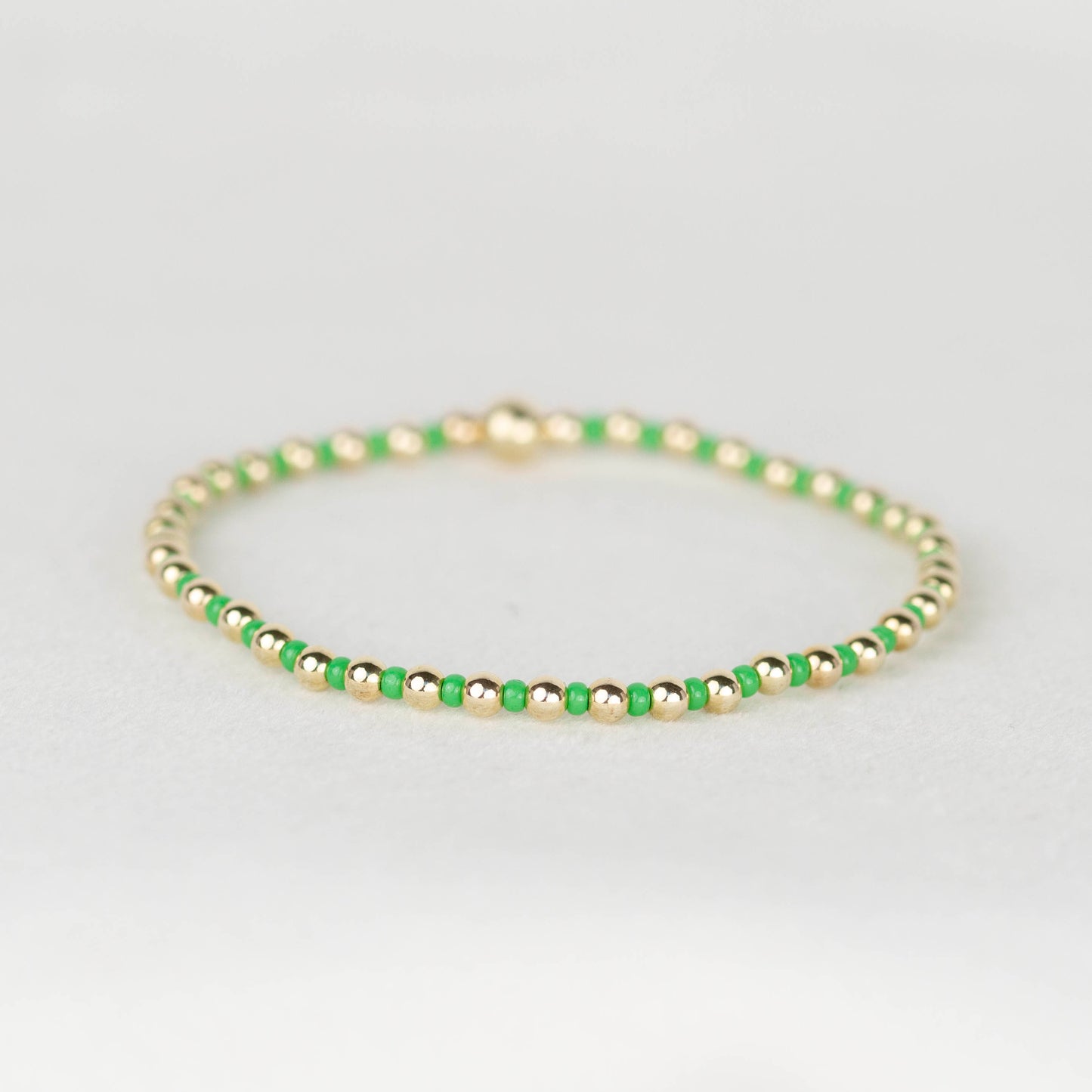 Green bright Bella seed bead alternating with 14k gold filled or sterling silver beaded stretch bracelet 
