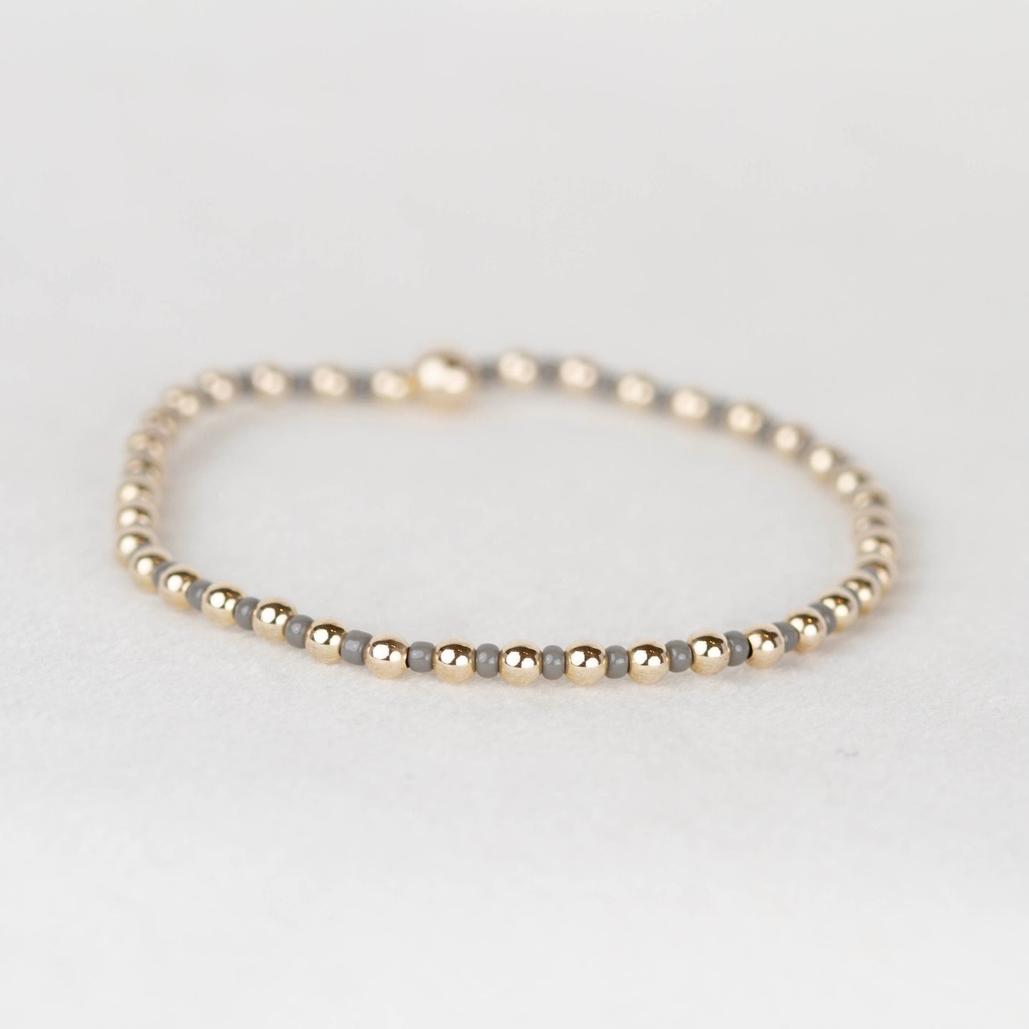 Dark gray Bella seed bead alternating with 14k gold filled or sterling silver beaded stretch bracelet 
