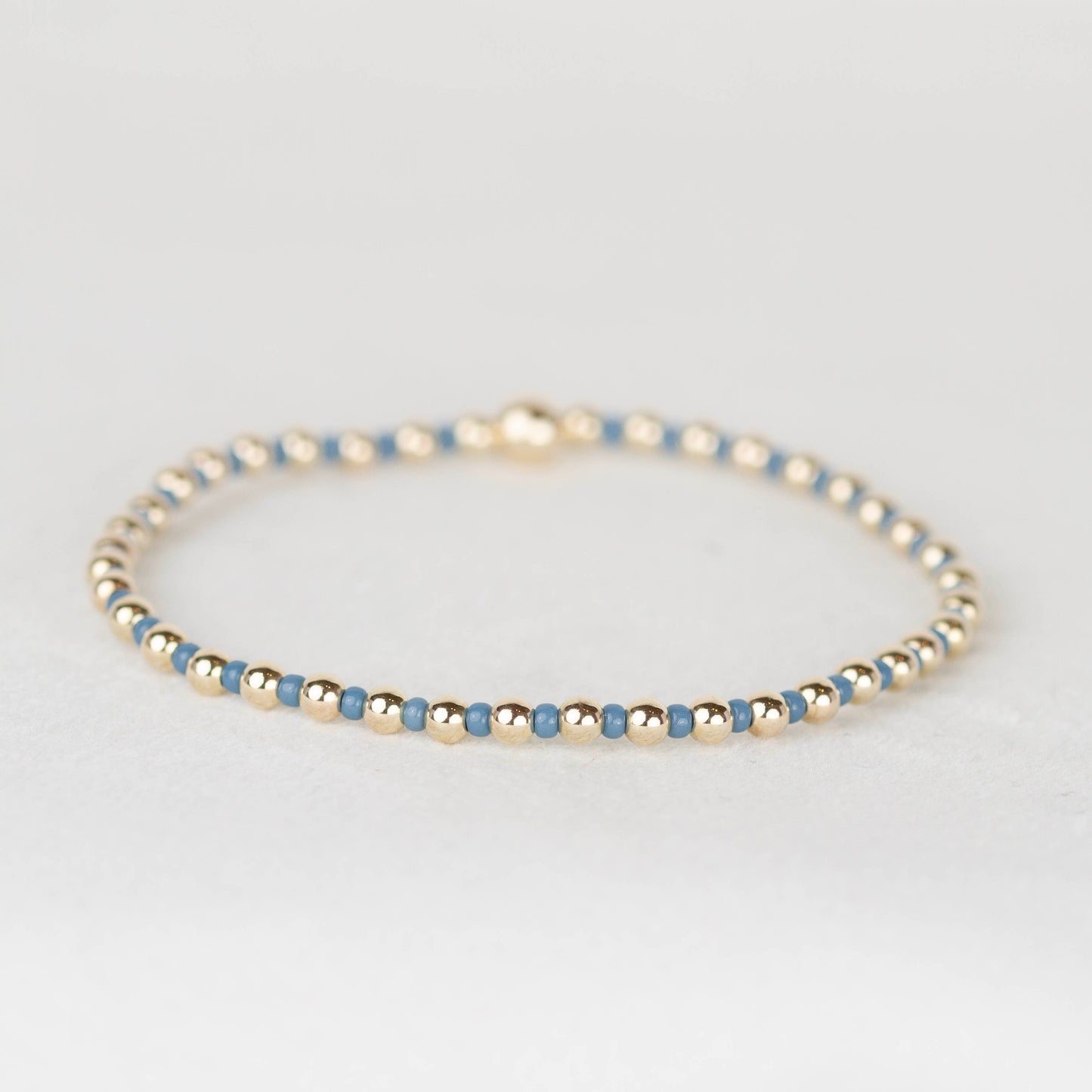Steel blue Bella seed bead alternating with 14k gold filled or sterling silver beaded stretch bracelet 

