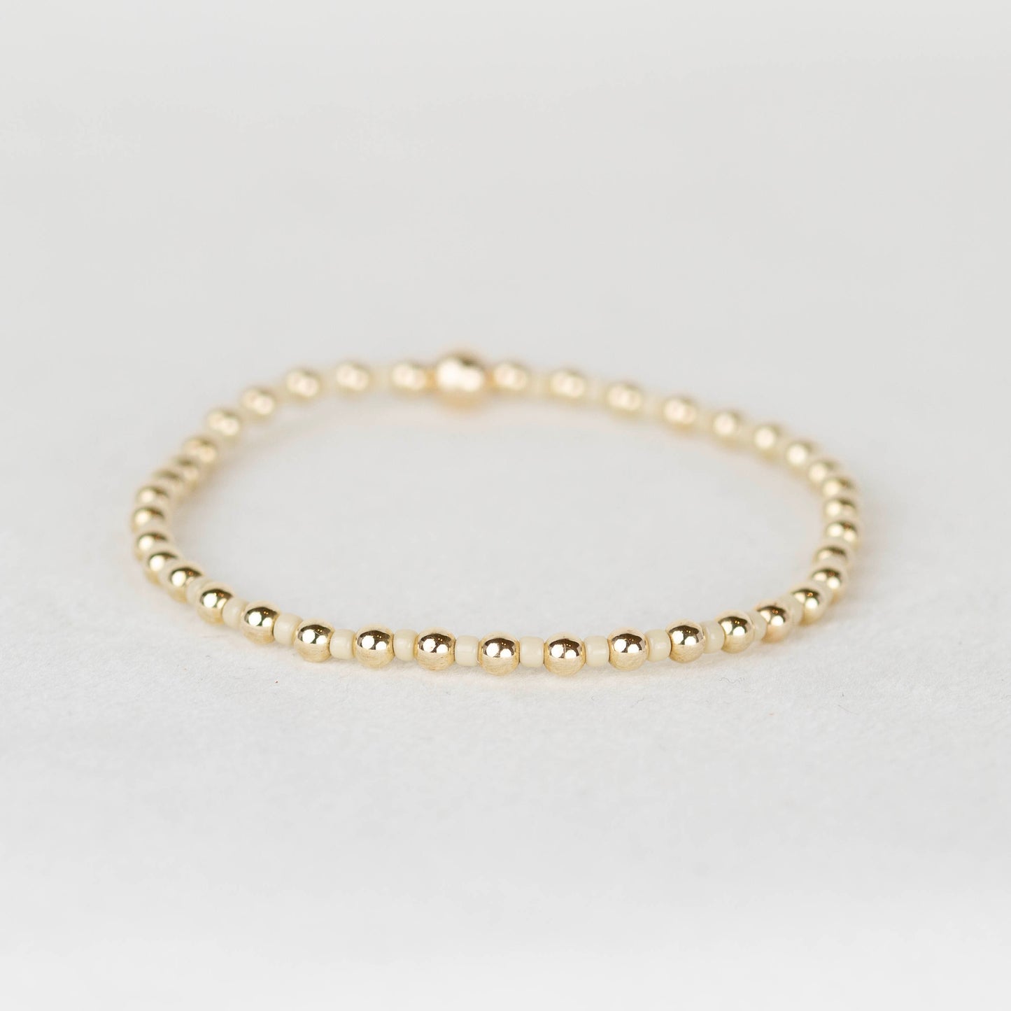 Creamy tan Bella seed bead alternating with 14k gold filled or sterling silver beaded stretch bracelet